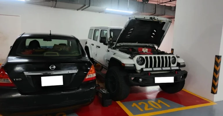 A car body repair Dubai service showing a black sedan and a white Jeep undergoing inspection in an indoor workshop.